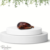 Tortoiseshell clutch on a white pedestal with greenery above, featuring the 'Parcelona' brand.