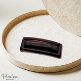 Brown rectangular hair barrette on a ceramic pot with 'Parcelona' branding.