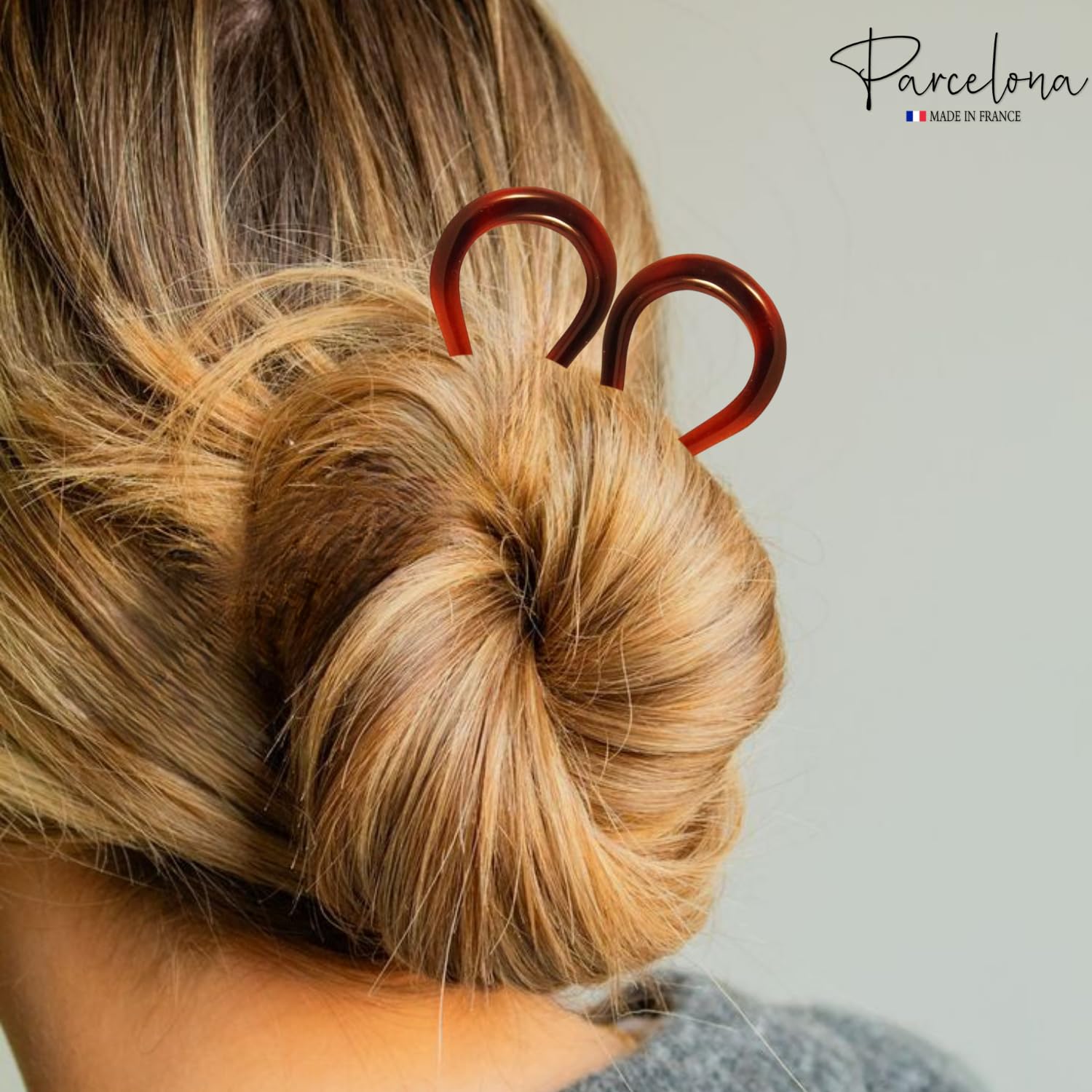 model with a bun holding a hair tie, with 'Parcelona' brand logo.