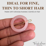Pink hair clip held between fingers with text about hair type suitability and brand name.