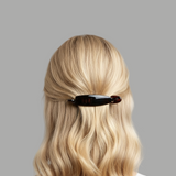Blonde hair with a brown hair clip on a grey background