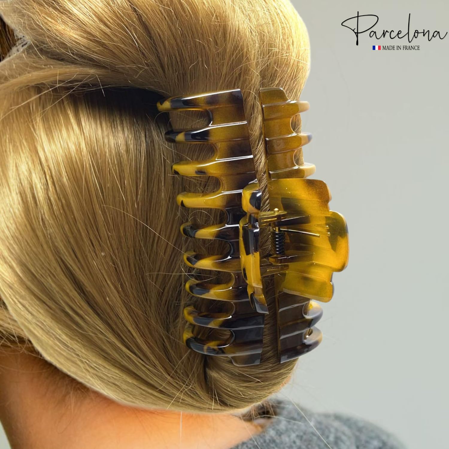 Hair clip in blonde hair with 'Parcelona' branding on a gray background