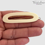 Ivory hair clip barrette held in a hand against a white background, branded 'French Amie'.