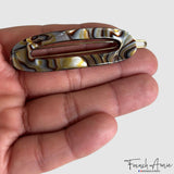 hair clip held in a hand with 'French Amie' branding.