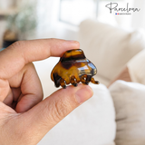 Hand holding a mini hair clip with 'Parcelona' branding in the background