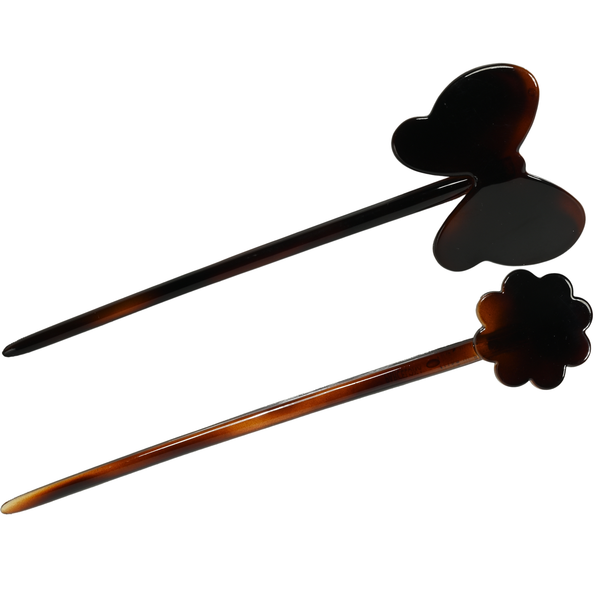 Two tortoiseshell hair sticks with heart and flower designs on a white background