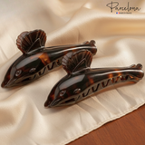 Dolphin tortoise-shell hair claws placed on satin fabric for a lifestyle display