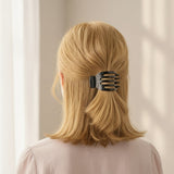 Person with blonde hair wearing a black hair clip against a neutral background