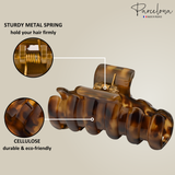 Brown hair clip with metal spring and cellulose material, labeled 'Parcelona' on a beige background.
