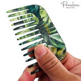 Tropical leaf-patterned comb held by a hand with 'Parcelona' branding.