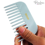 Light blue comb held by a hand with 'Parcelona' branding on a white background