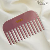Pink comb with 'Parcelona' branding on a white fabric background
