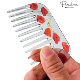 Hair comb with red poppy design held by a hand, brand 'Parcelona' visible